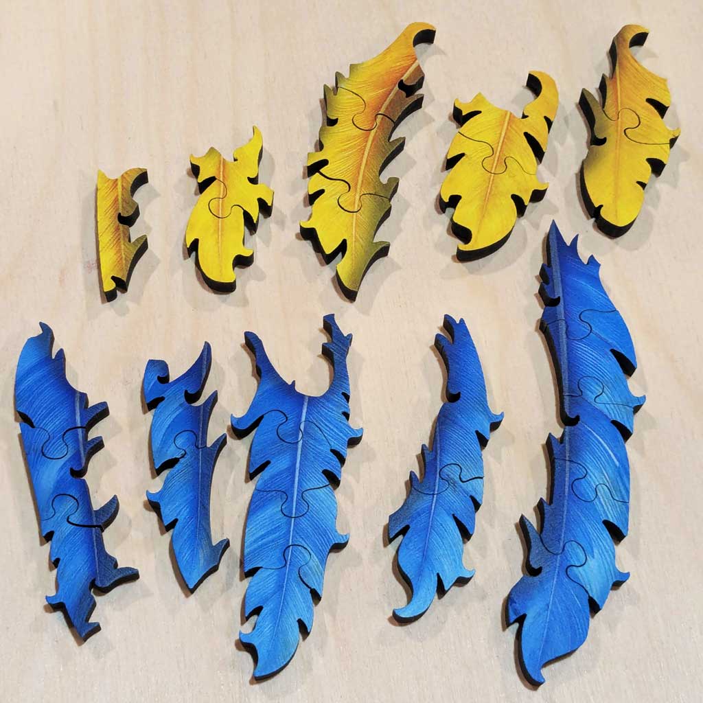Loose yellow and blue feather-shaped wooden puzzle pieces on table