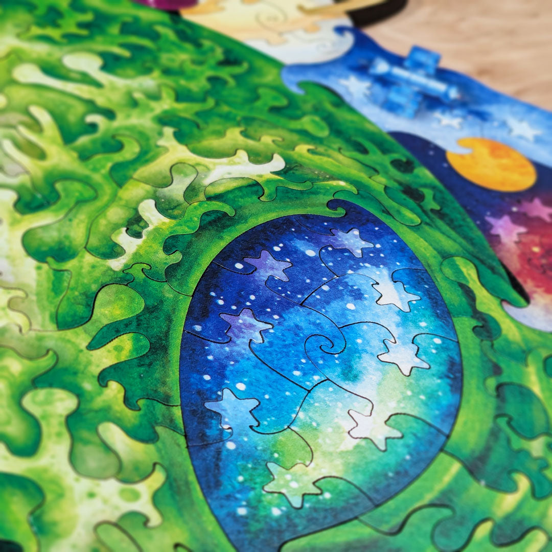 Close-up of the alien eye area showing color-line cut pieces following the swirling green textures of the alien face, with the galaxy-filled eye visible in blue and teal tones.