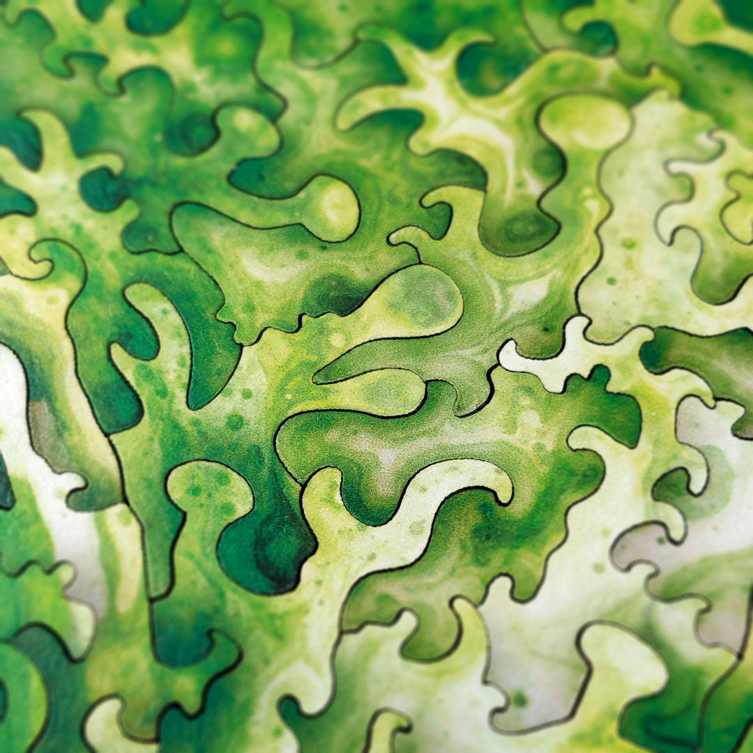 Extreme close-up of the alien face's forehead and crown, showing the intricate color-line cut pattern following the swirling green and cream watercolor textures of the alien skin.