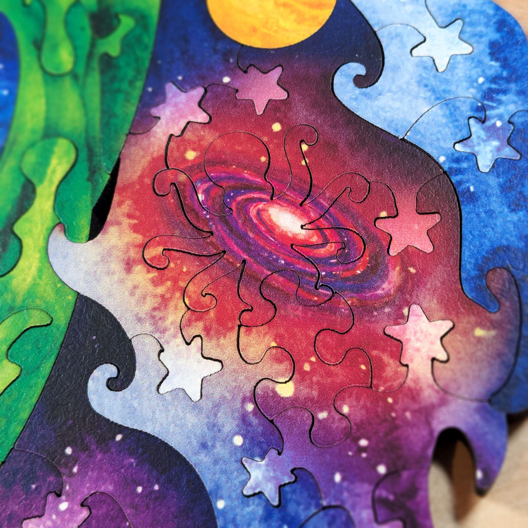 Close-up of the spiral galaxy section in deep purples and reds, surrounded by star-shaped pieces and the jagged outer edge of the puzzle silhouette.