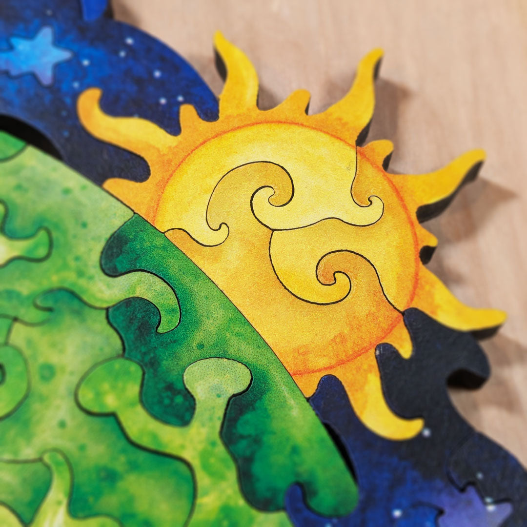 Close-up of the sun piece in the upper corner, showing bright yellow and orange color-line cut pieces radiating outward against the deep blue starfield background.
