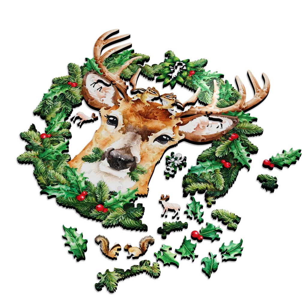 Partially assembled “Under the Mistletoe” wooden jigsaw puzzle of a deer in a holiday wreath, with leaf and woodland animal pieces scattered around.